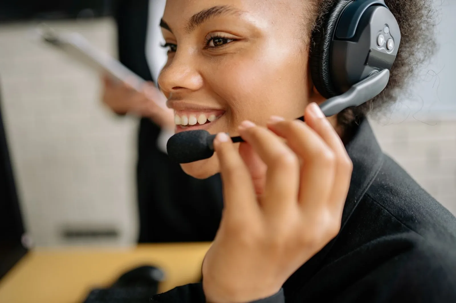 Operadora de atendimento sorrindo enquanto fala ao headset