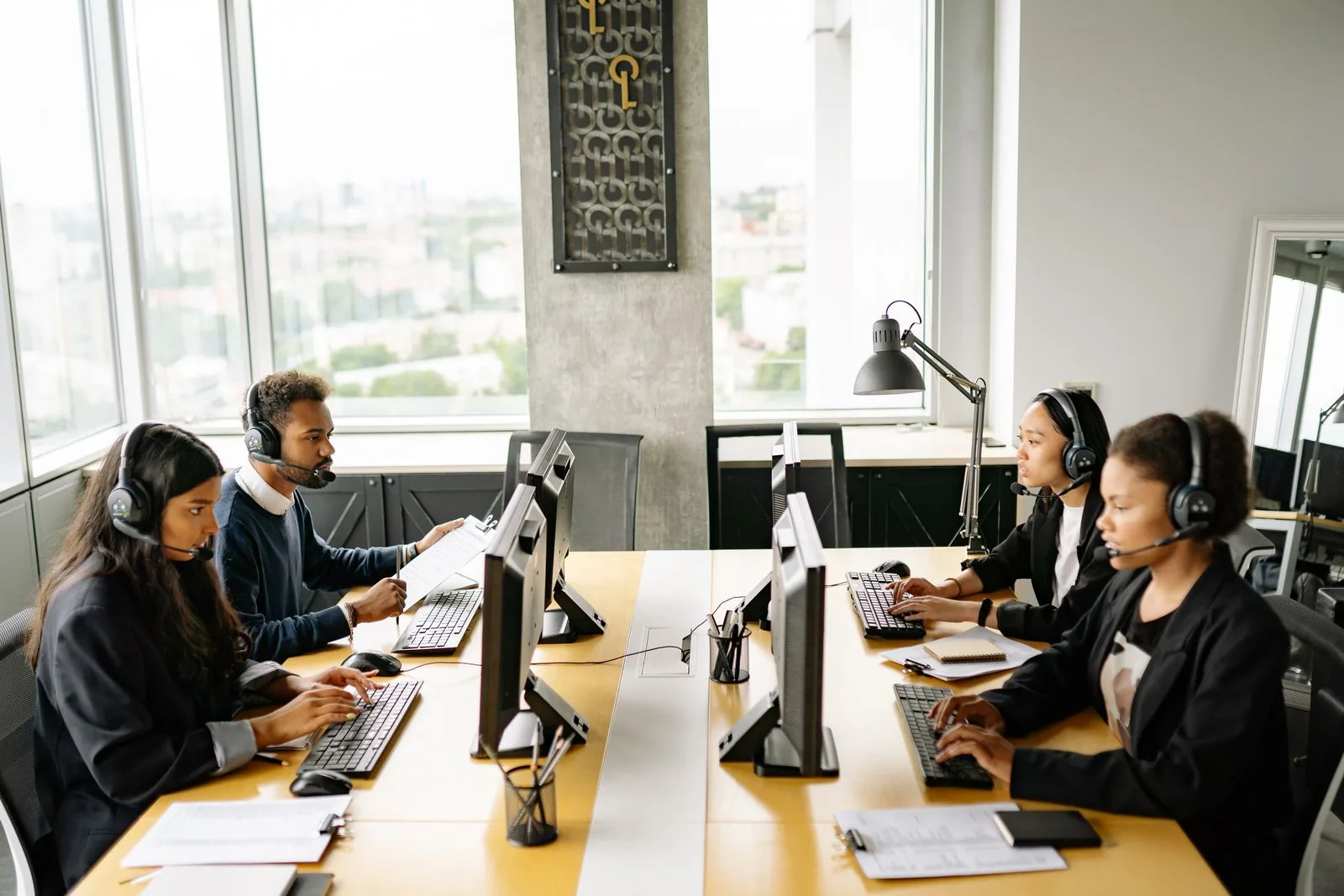 Equipe de atendimento com headsets, trabalhando nos computadores